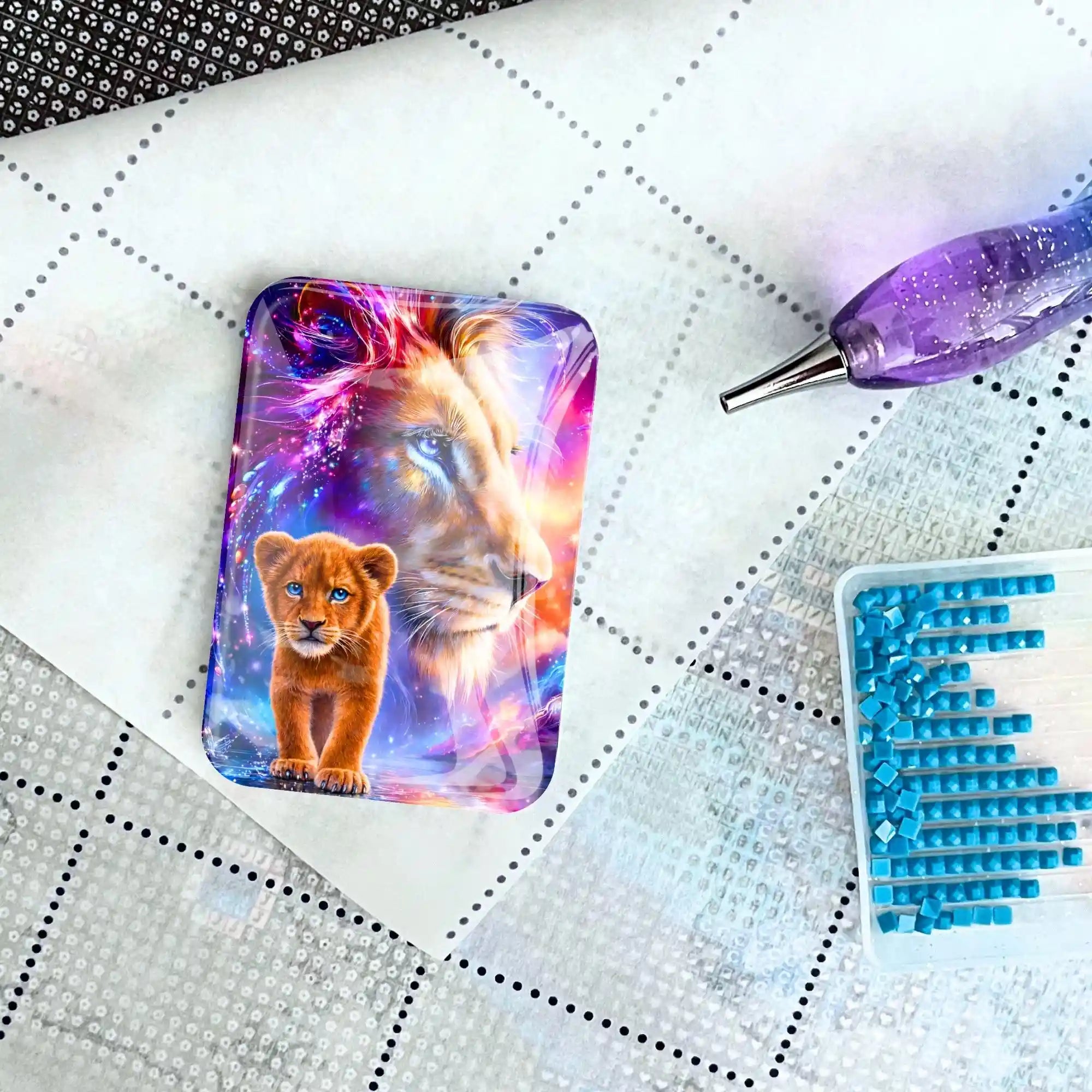 Magnetischer Cover Minder mit Löwen-Motiv für Diamond Painting auf einer Leinwand mit Stift und blauen Diamanten.