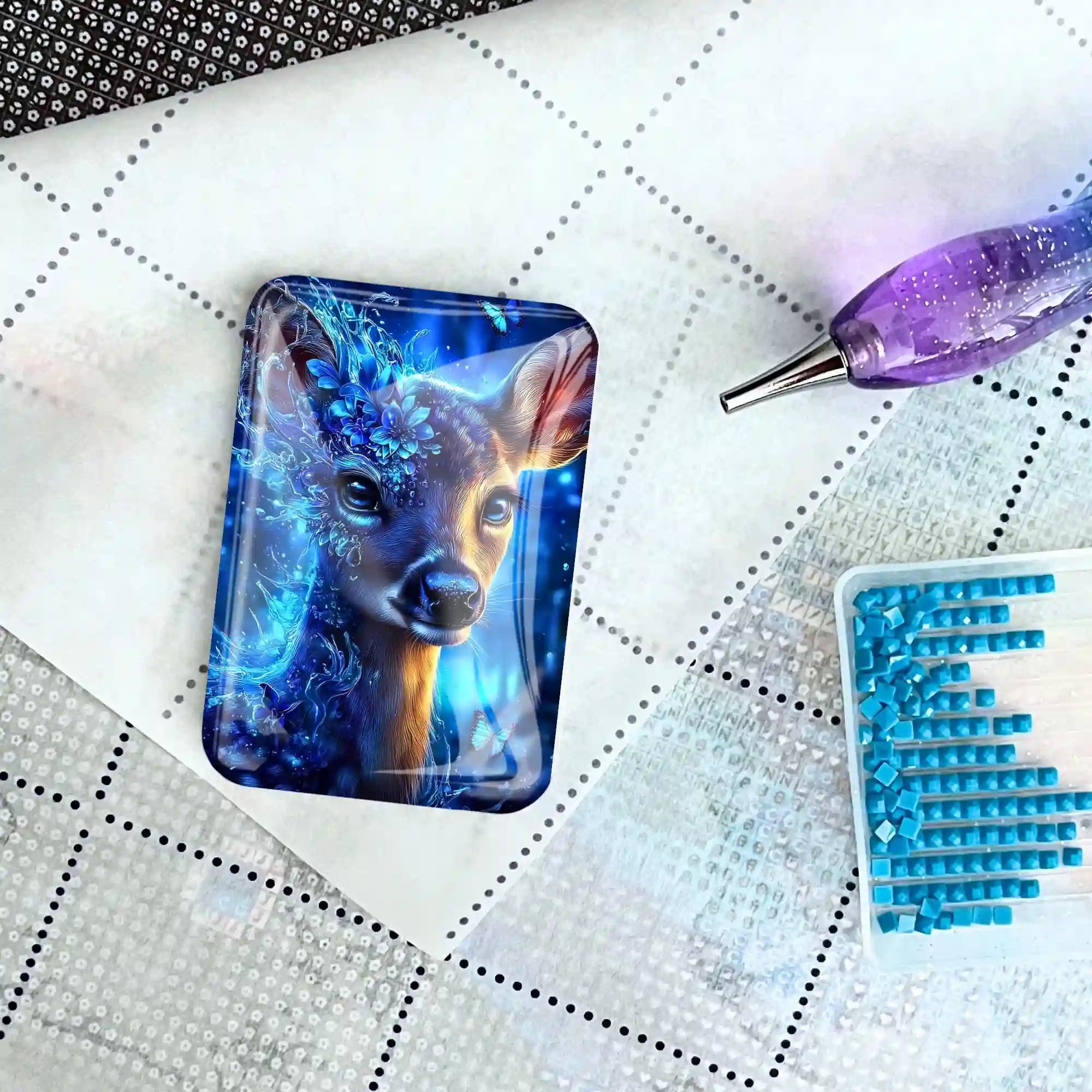 Magischer Cover Minder mit Reh-Motiv für Diamond Painting auf einer Leinwand mit Werkzeug und blauen Steinchen