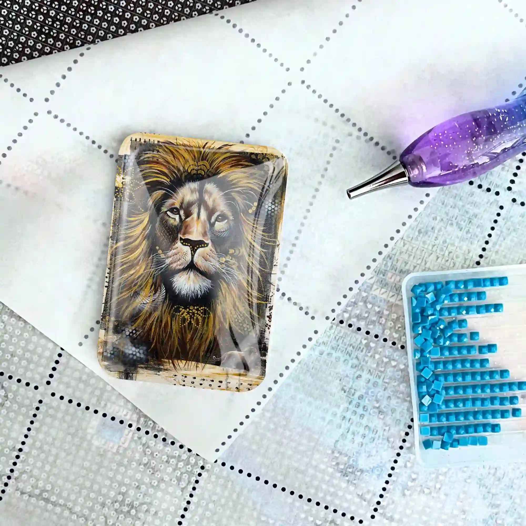 Löwen-Coverminder aus Glas für Diamond Painting auf einer Leinwand mit Stift und blauen Diamanten