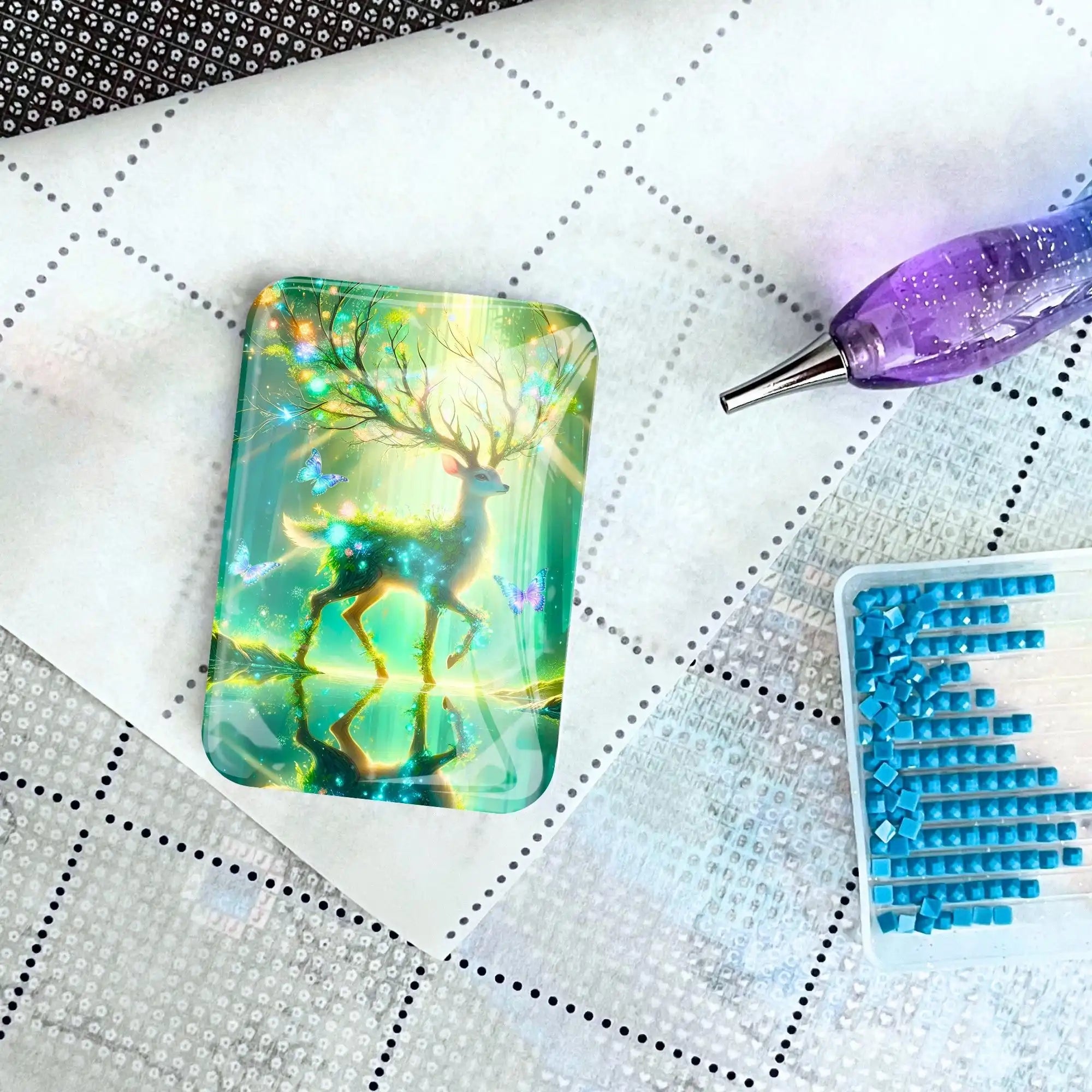 Magischer Cover Minder mit Hirsch-Motiv für Diamond Painting auf einer Leinwand mit Applikator und blauen Steinen.